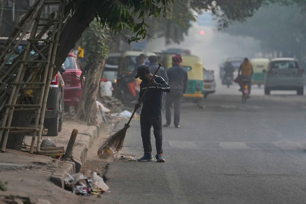 A municipal worker sweeps a road on a fog-filled morning in New Delhi, India, Tuesday, Nov. 18, 2025. (AP Photo/Manish Swarup)