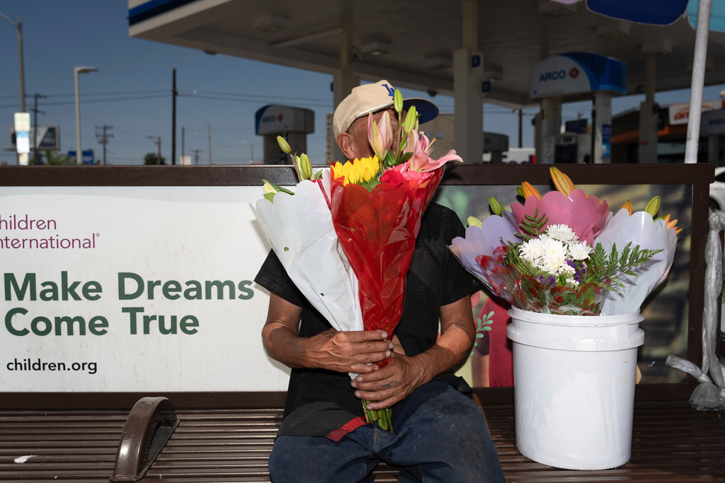 FILE - Flower vendor Jose, an immigrant from Mexico, sits for a photo with his face covered by flowers outside a gas station in Los Angeles, Friday, Aug. 8, 2025. (AP Photo/Jae C. Hong, File)