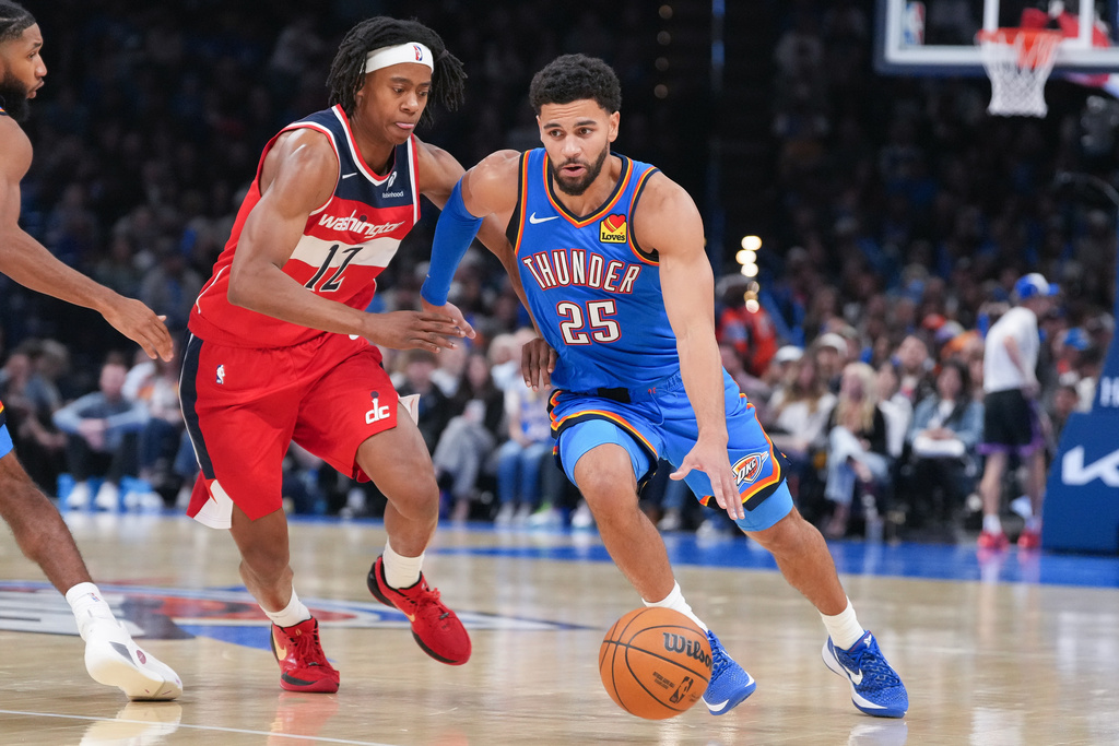 Oklahoma City Thunder guard Ajay Mitchell (25) drives past Washington Wizards guard Tre Johnson (12) during the second half of an NBA basketball game, Thursday, Oct. 30, 2025, in Oklahoma City. (AP Photo/Kyle Phillips)