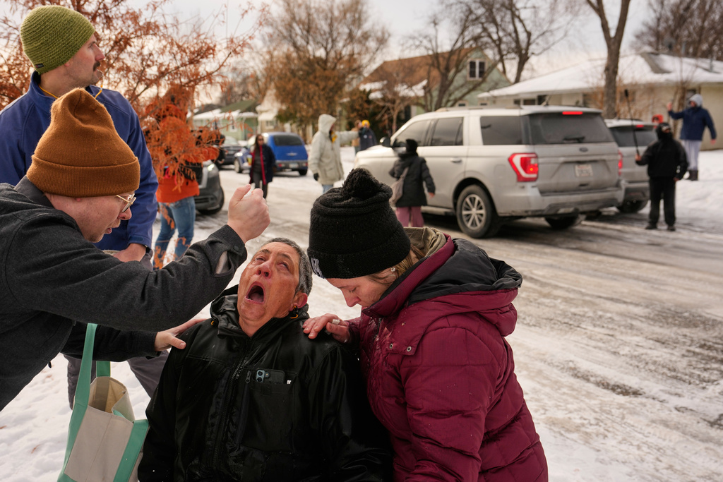 Bystanders are treated after being pepper sprayed as federal immigration officers make an arrest Sunday, Jan. 11, 2026, in Minneapolis. (AP Photo/John Locher)