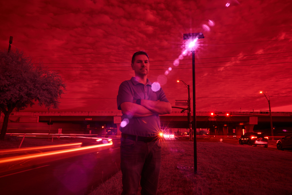 Alek Schott, who filed a lawsuit alleging violations of his constitutional rights when Texas sheriff's deputies stopped and searched his vehicle at the request of Border Patrol agents, is photographed, as an infrared beam of light from a Flock Safety automatic license plate reader records passing vehicles driving near his neighborhood, Oct. 16, 2025, in Houston. (AP Photo/David Goldman)
