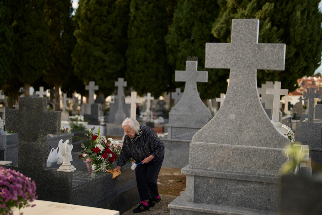 A woman cleans a grave on All Saints' Day, a Catholic holiday to reflect on the saints and deceased relatives, at the municipal cemetery in Campo Real, Spain, Saturday, Nov. 1, 2025. (AP Photo/Manu Fernandez)