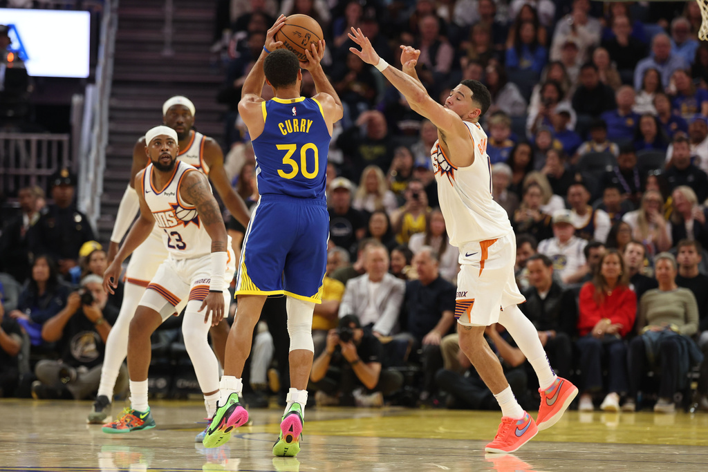 Golden State Warriors guard Stephen Curry (30) shoots against Phoenix Suns guard Devin Booker (1) during the first half of an NBA basketball game in San Francisco, Tuesday, Nov. 4, 2025. (AP Photo/Jed Jacobsohn)