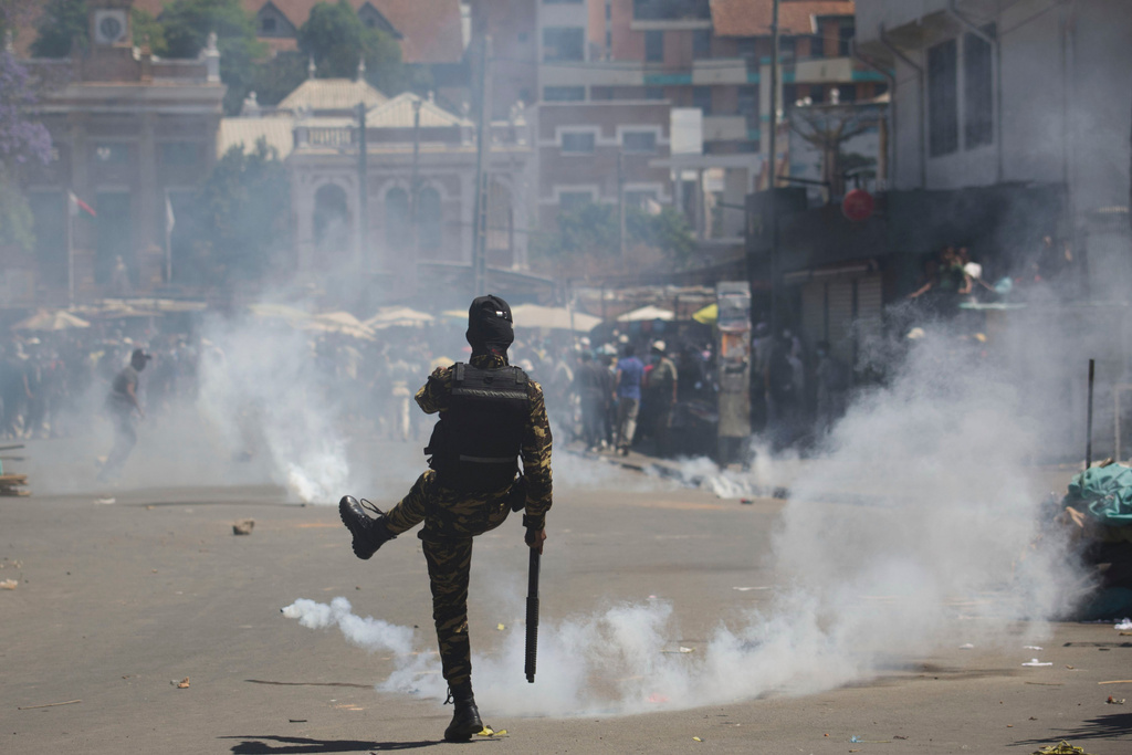 A police officer kicks back a teargas canister during a protest calling for the president to step down in Antananarivo, Madagascar, Thursday, Oct. 9, 2025. (AP Photo/Alexander Joe)