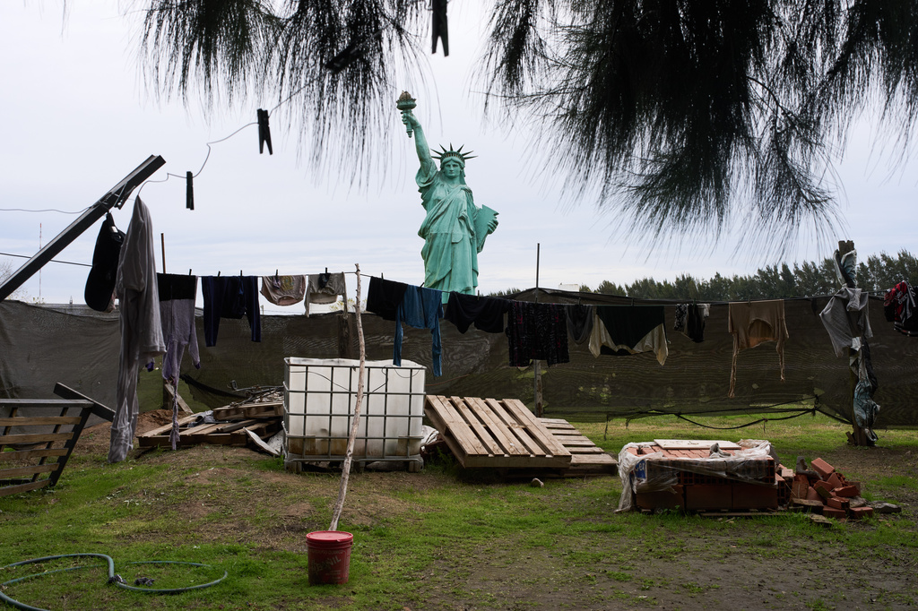 A replica of the Statue of Liberty stands behind clothes hanging to dry at a home on outskirts of Buenos Aires, Argentina, Wednesday, June 24, 2026. (AP Photo/Rodrigo Abd)