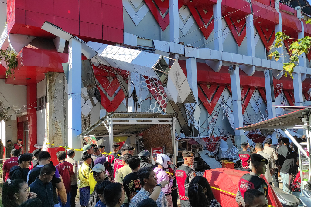 Onlookers gather as police officers inspect a damaged building following an earthquake in Manado, North Sulawesi, Indonesia, Thursday, April 2, 2026. (AP Photo/Tonny Rarung)