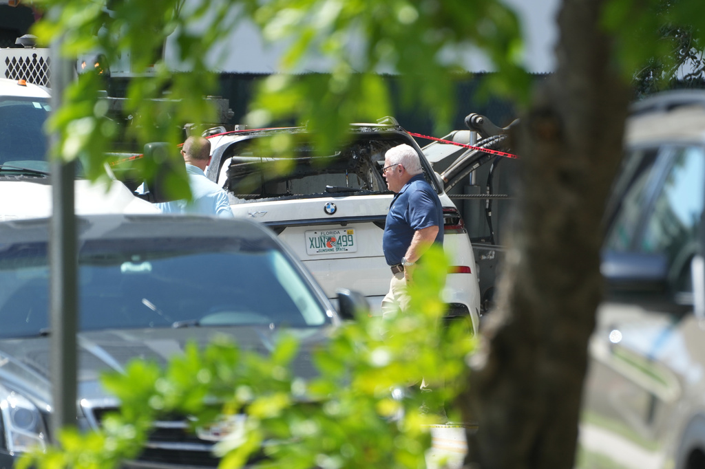 Investigators walk around damaged cars after a large construction crane collapsed Monday, Sept. 14, 2026, in Miami. (AP Photo/Marta Lavandier)