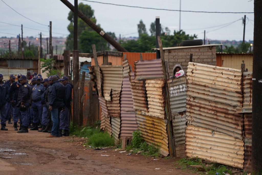 South African police gather at the scene of a mass shooting where gunmen killed nine and injured at least 10 in a pub in Bekkersdal, South Africa, Sunday, Dec. 21, 2025. (AP Photo/ Alfonso Nqunjana)