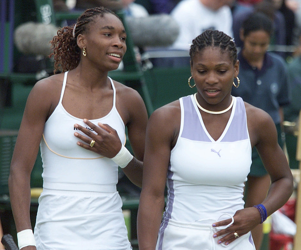 FILE -Venus Williams, left, and sister Serena talk together, during their Women's Doubles match against Irina Spirlea and Caroline Vis, at Wimbledon, July 4, 2000. (AP Photo/Alastair Grant, File)
