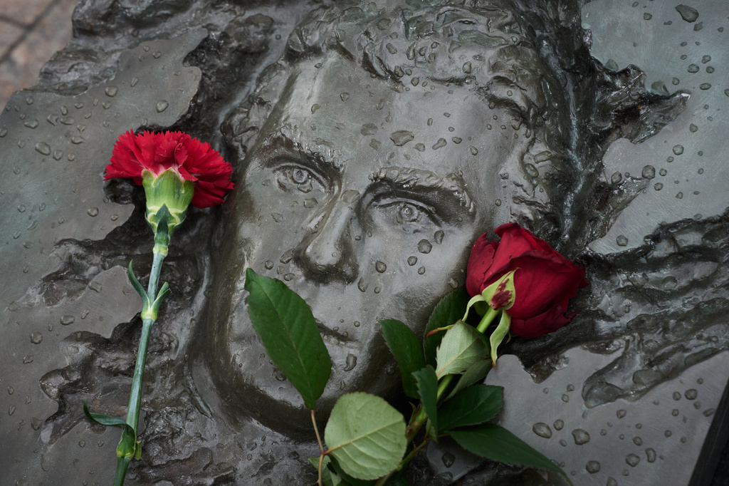Red flowers lie on a bas-relief of firefighter Georgy Popov atop of his grave at the Mitinskoye Cemetery where several victims of the Chernobyl nuclear disaster are buried, marking the 40th anniversary of the explosion and fire at the Chernobyl nuclear power plant in Ukraine, outside Moscow, Sunday, April 26, 2026. (AP Photo/Alexander Zemlianichenko)