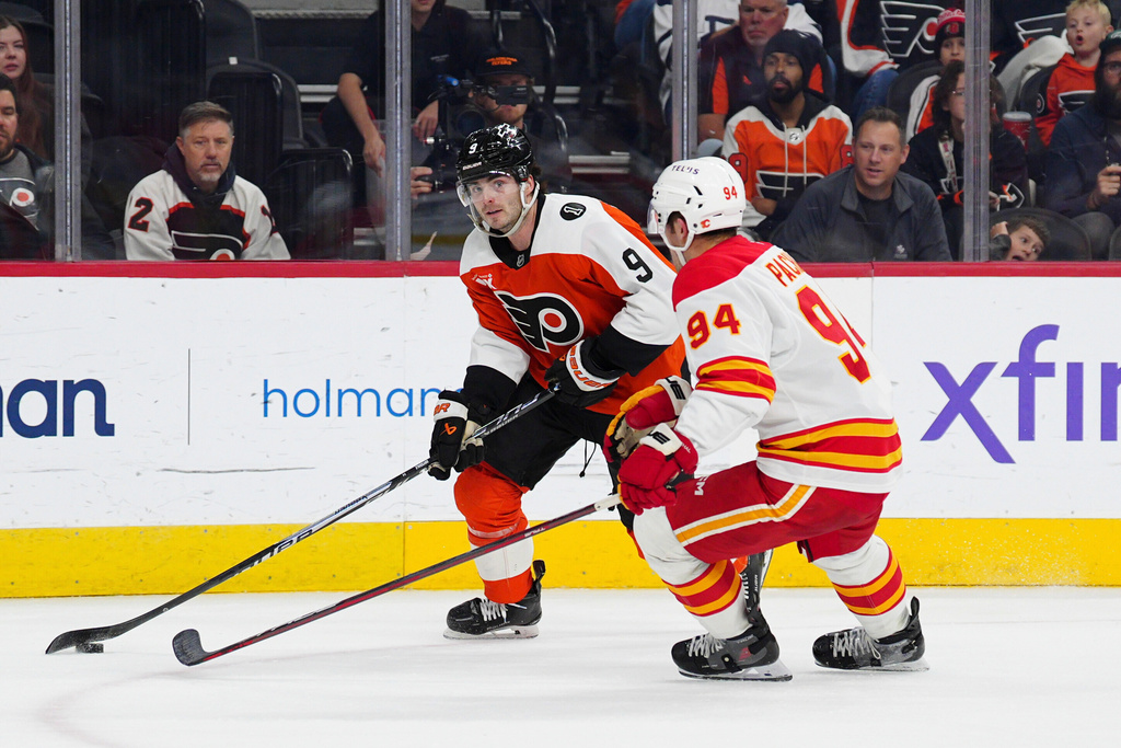 Philadelphia Flyers' Jamie Drysdale, left, skates with the puck against Calgary Flames' Brayden Pachal (94) during the second period of an NHL hockey game, Sunday, Nov. 2, 2025, in Philadelphia. (AP Photo/Derik Hamilton)