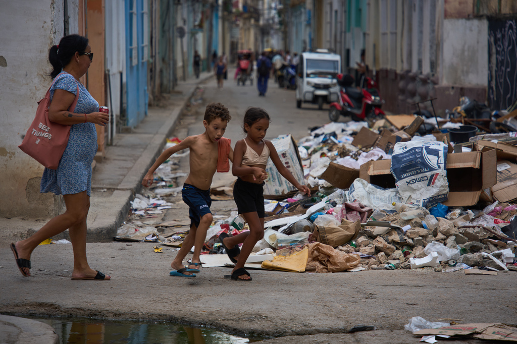 Children run past a pile of trash accumulated on a street during a blackout in Havana, Cuba, Monday, July 6, 2026. (AP Photo/Ramon Espinosa)
