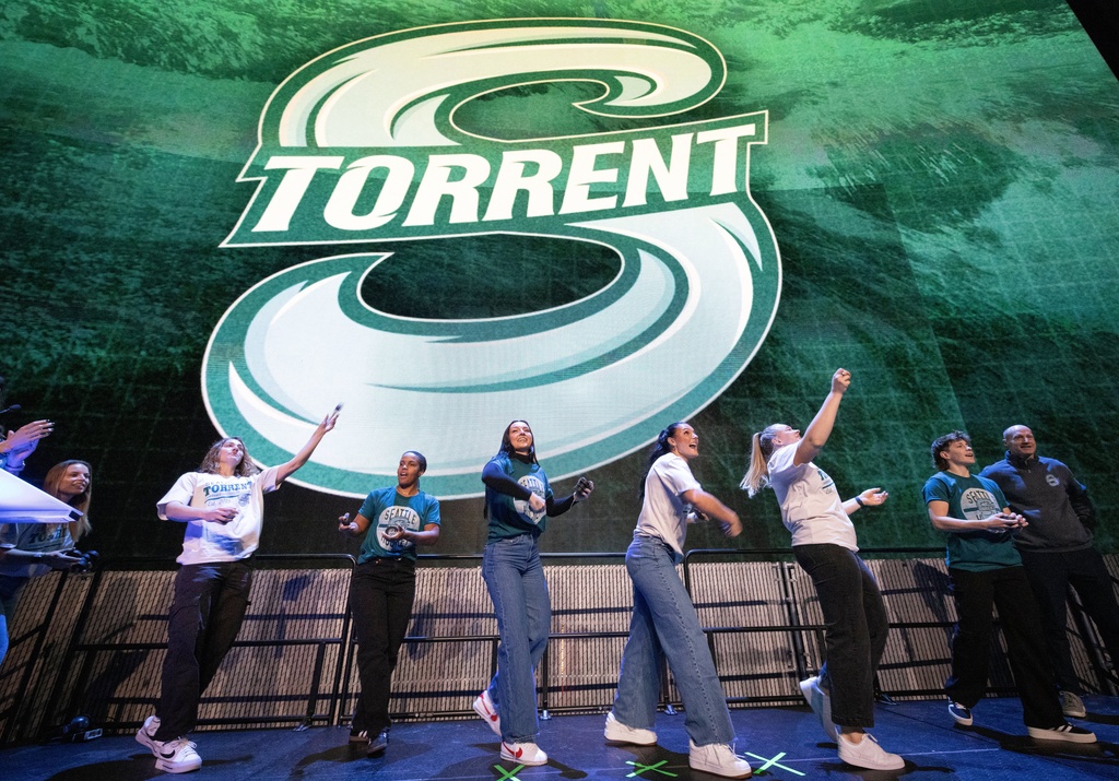 Seattle Torrent members toss gifts to the crowd during an event unveiling the PWHL hockey team's new logo and name, Thursday, Nov. 6, 2025, in Seattle. (Ken Lambert/The Seattle Times via AP)