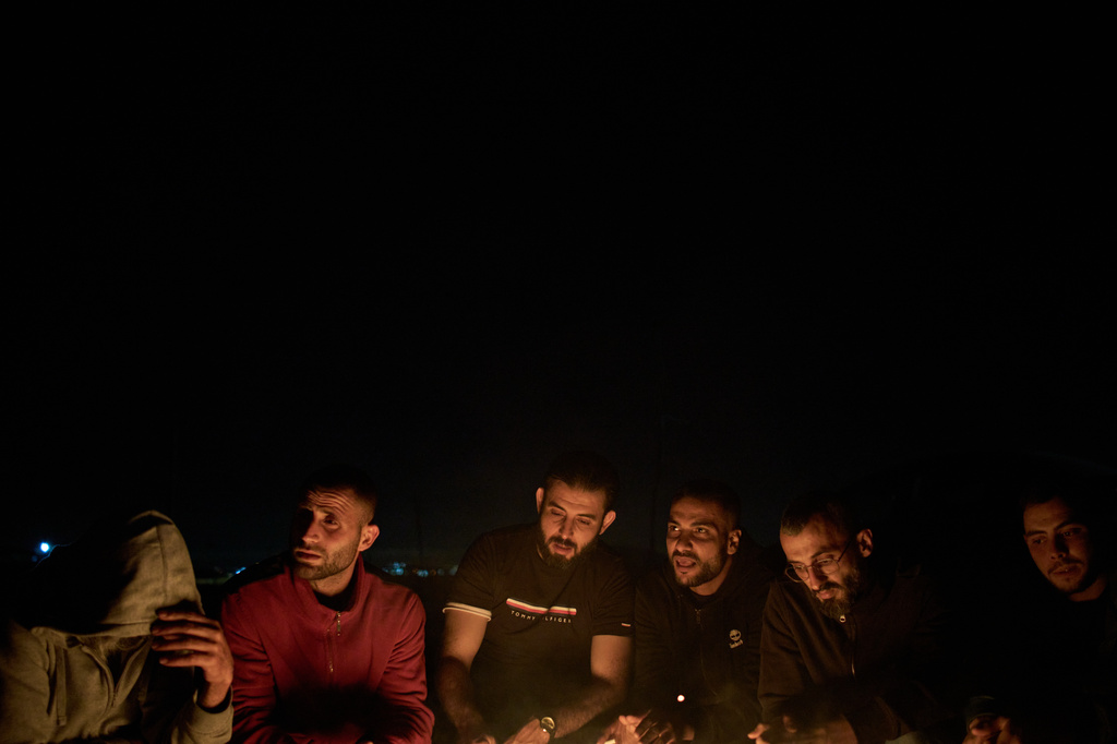 Palestinians sit next to the bonfire as they take part in a night watch to prevent Israeli settler attacks in the West Bank village of Sinjil, Thursday, July 16, 2026. (AP Photo/Leo Correa)