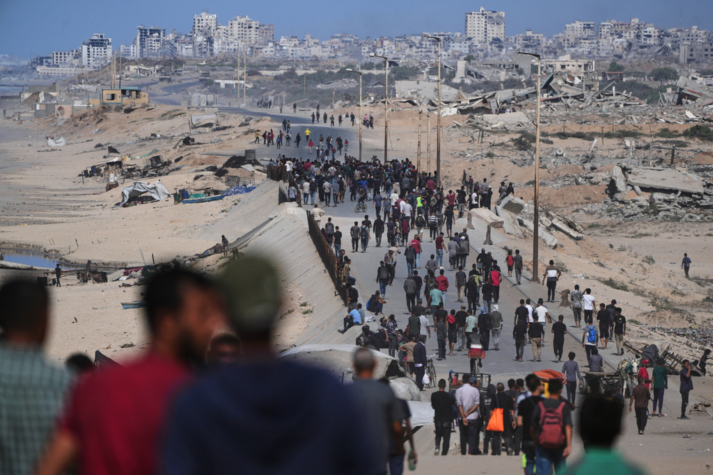 Displaced Palestinians gather on the coastal road near Wadi Gaza after the announcement that Israel and Hamas had agreed to the first phase of a peace plan to pause the fighting, as Israeli tanks block the road leading to Gaza City, in the central Gaza Strip, Thursday, Oct. 9, 2025. (AP Photo/Abdel Kareem Hana)