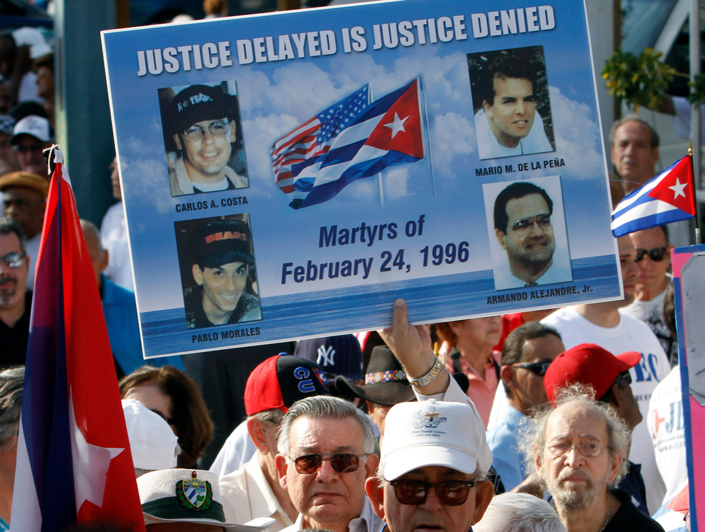 FILE - Mario de la Pena carries a poster with the photos of the four pilots shot down by Cuban Migs, his son Mario de la Pena, top right, was among the pilots, during a freedom for Cuba march in Miami, Feb. 24, 2011. (AP Photo/Alan Diaz, File)