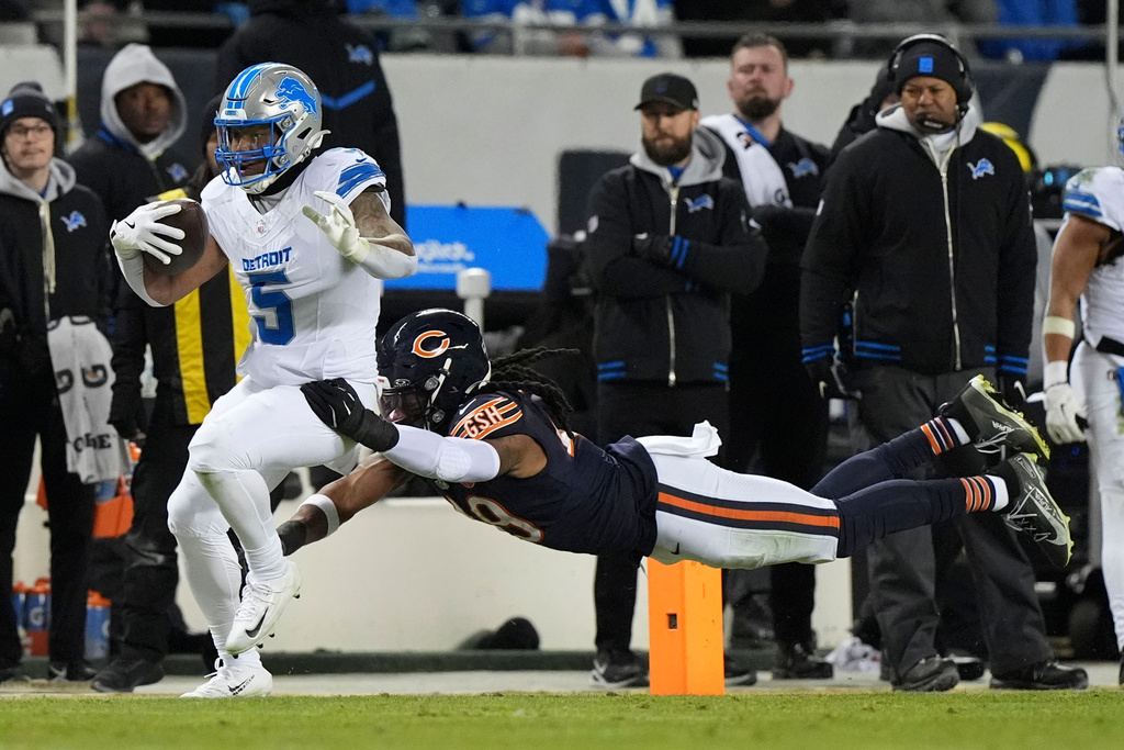 Detroit Lions running back David Montgomery (5) runs from Chicago Bears linebacker Tremaine Edmunds (49) during the second half of an NFL football game, Sunday, Jan. 4, 2026, in Chicago. (AP Photo/Nam Y. Huh)