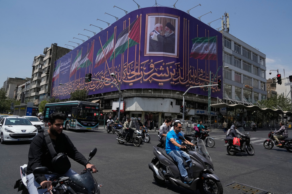 Vehicles drive past a billboard showing a photo of the late Iranian Supreme Leader Ayatollah Ali Khamenei, right, greeting the late Hamas leader Ismail Haniyeh, and Iranian and Palestinian flags, at an intersection in downtown Tehran, Iran, Saturday, Aug. 1, 2026. (AP Photo/Vahid Salemi)