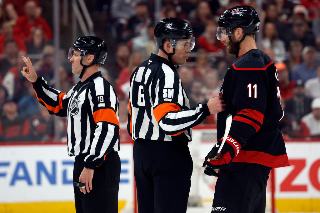 Referee Gord Dwyer (19) announces a call while referee Francis Charron (6) espeaks to Carolina Hurricanes' Jordan Staal (11) during the third period of Game 2 of an NHL hockey Stanley Cup second-round playoff series against the Philadelphia Flyers in Raleigh, N.C., Monday, May 4, 2026. (AP Photo/Karl DeBlaker)