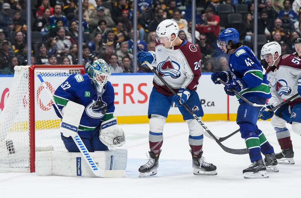 Vancouver Canucks goalie Kevin Lankinen (32) makes the save as teammate Quinn Hughes (43) and Colorado Avalanche's Ross Colton (20) and Gavin Brindley (54) watch during the second period of an NHL hockey game in Vancouver, B.C., Sunday, Nov. 9, 2025. (Darryl Dyck/The Canadian Press via AP)