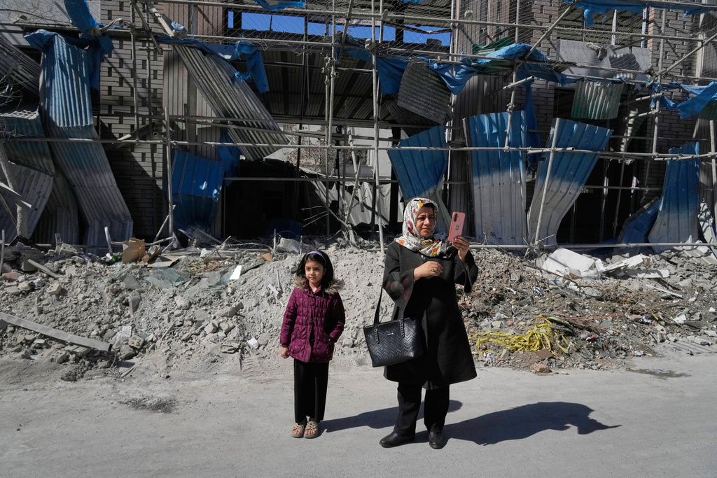 A woman takes images with her smart phone in front of a building which was damaged after a strike on a police station amid the U.S.–Israeli military campaign in Tehran, Iran, Tuesday, March 3, 2026. (AP Photo/Vahid Salemi)