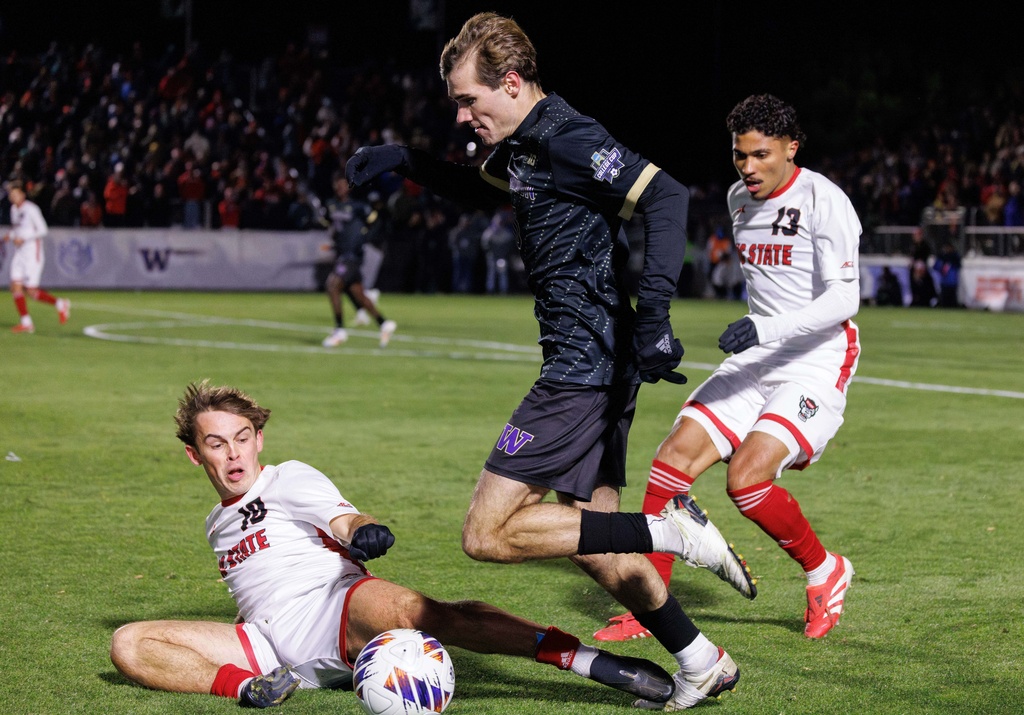 Washington's Richie Aman, center, handles the ball as North Carolina State's Taig Healy (10) and Calem Tommy (13) defend during the first half of the NCAA College Cup National Championship soccer final in Cary, N.C., Monday, Dec. 15, 2025. (AP Photo/Ben McKeown)