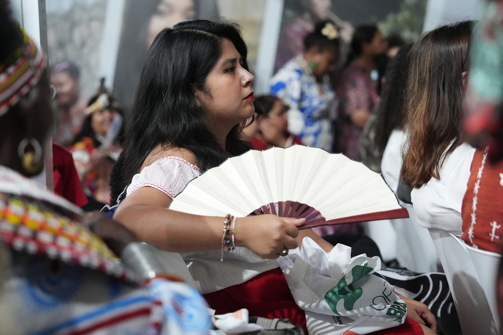 An attendee fans themselves at the opening of the Indigenous Peoples Pavilion at the COP30 U.N. Climate Summit, Monday, Nov. 10, 2025, in Belem, Brazil. (AP Photo/Joshua A. Bickel)