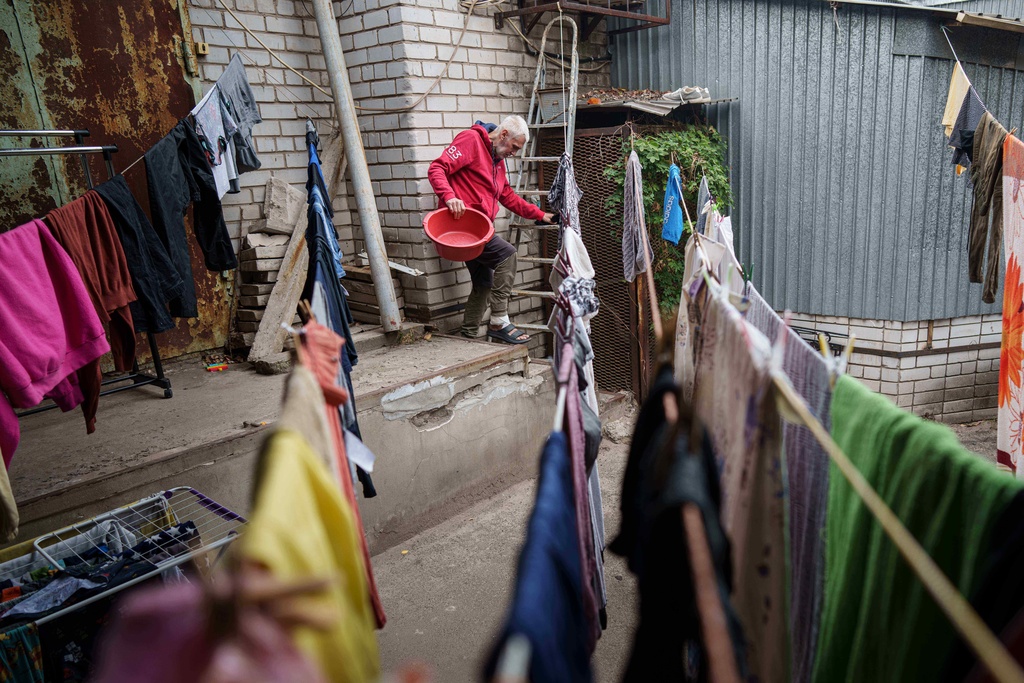 A man works to dry washed clothing at a hostel for the displaced in Dnipro, Ukraine, Wednesday, Oct. 8, 2025. (AP Photo/Evgeniy Maloletka)