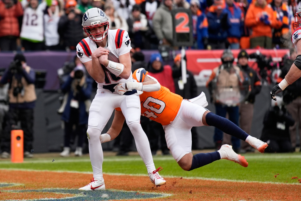 New England Patriots quarterback Drake Maye scores past Denver Broncos linebacker Justin Strnad during the first the half of the AFC Championship NFL football game, Sunday, Jan. 25, 2026, in Denver. (AP Photo/John Locher)