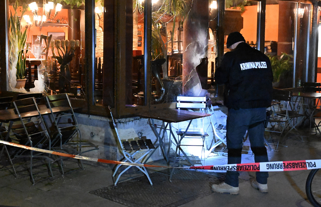 An investigator checks the damage as he stands outside an Israeli restaurant where the windows were broken early Friday, April 10, 2026, in Munich, Germany. (Felix Hörhager/dpa via AP)