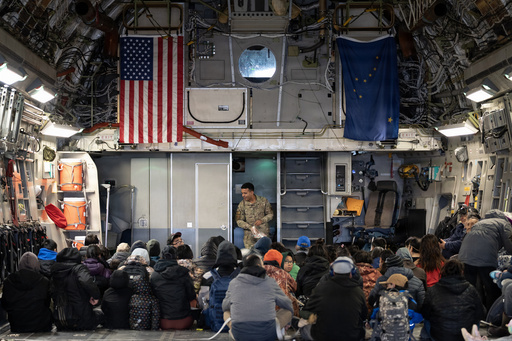 In this photo provided by the Alaska National Guard, Alaska Air National Guard Staff Sgt. Angel Reyes distributes hearing protection to passengers while evacuating Alaskans displaced in the aftermath of Typhoon Halong out of Bethel, Alaska, Wednesday, Oct. 15, 2025. (Alaska National Guard via AP) In this photo provided by the Alaska National Guard, Alaska Air National Guard Staff Sgt. Angel Reyes distributes hearing protection to passengers while evacuating Alaskans displaced in the aftermath of Typhoon Halong out of Bethel, Alaska, Wednesday, Oct. 15, 2025. (Alaska National Guard via AP)