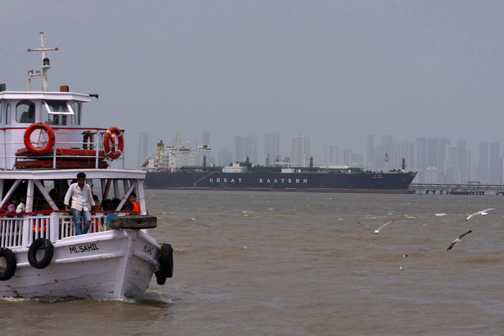 A tourist ferry sails past the Indian flagged LPG carrier Jag Vasant transporting liquefied petroleum gas, at the Mumbai Port in Mumbai, India, after it arrived clearing the Strait of Hormuz, Wednesday, April 1, 2026.(AP Photo/Rafiq Maqbool)