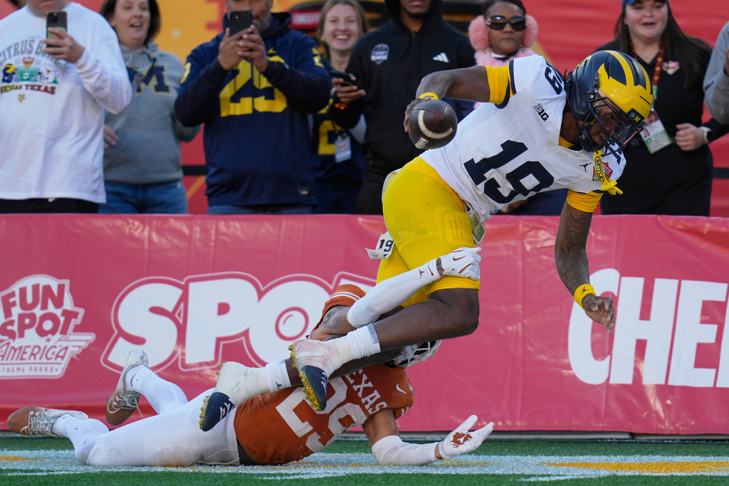 Michigan quarterback Bryce Underwood (19) is run out of bounds by Texas defensive back Graceson Littleton (29) during the first half of the Citrus Bowl NCAA college football game, Wednesday, Dec. 31, 2025, in Orlando, Fla. (AP Photo/John Raoux)