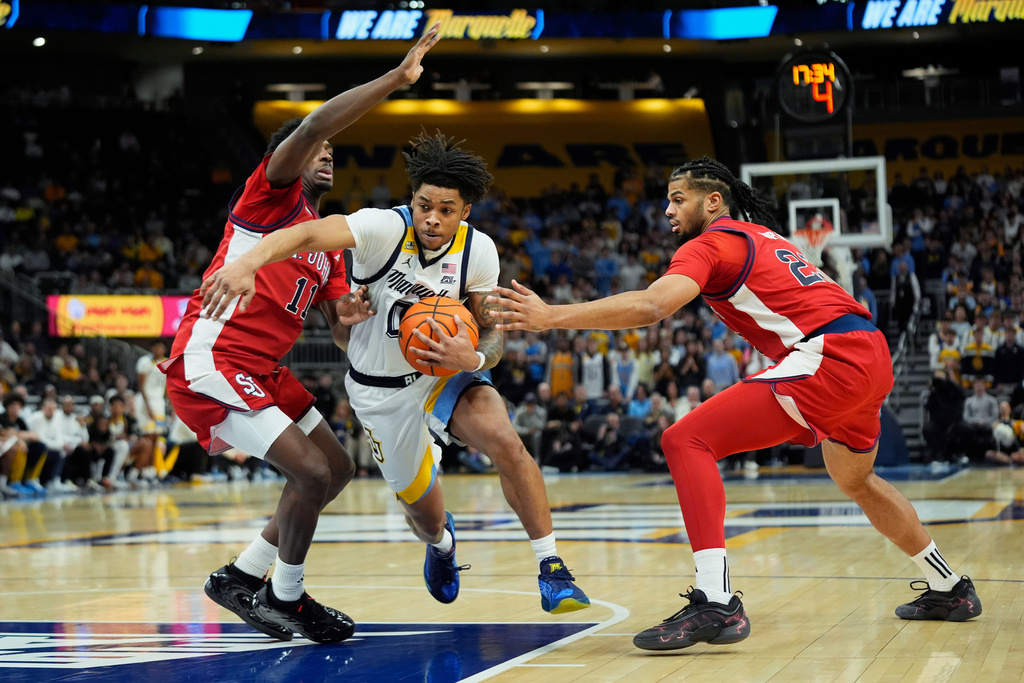 Marquette's Nigel James Jr., middle, drives to the basket between St. John's' Ian Jackson (11) and Zuby Ejiofor during the first half of an NCAA college basketball game Wednesday, Feb. 18, 2026, in Milwaukee. (AP Photo/Aaron Gash)