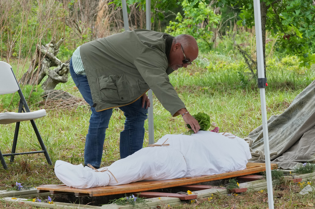 Scott King places a bouquet of flowers on the body of his brother Kenneth King at the Prairie Creek Conservation Cemetery, Tuesday, April 7, 2026, in Gainesville, Fla. (AP Photo/Marta Lavandier)