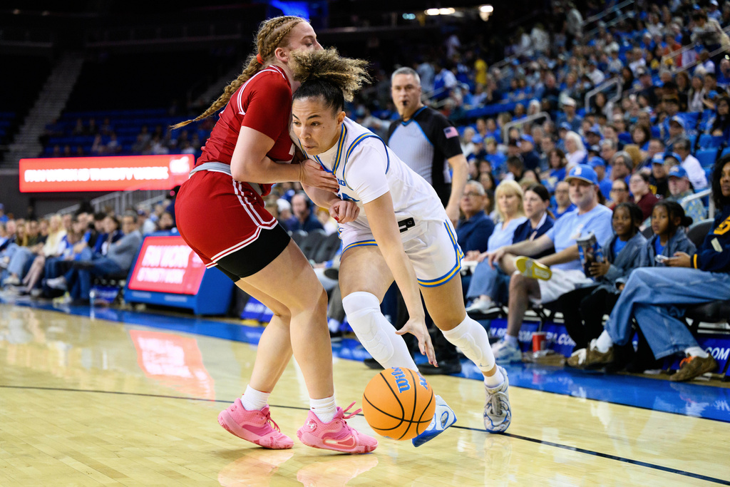 UCLA guard Kiki Rice (1) drives the ball against Wisconsin guard Laci Steele during the first half of an NCAA college basketball game, Sunday, Feb. 22, 2026, in Los Angeles. (AP Photo/William Liang)