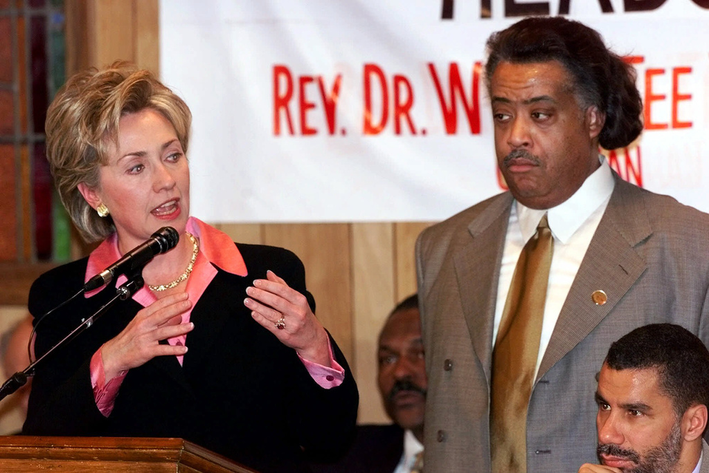 FILE - First lady Hillary Rodham Clinton delivers her speech at the National Action Network's Annual Martin Luther King Jr. Public Policy Forum as, from left, Assemblyman Keith Wright, Rev. Al Sharpton, and State Senator David Paterson look on Monday, Jan. 17, 2000, in New York. (AP Photo/Kathy Willens, File)