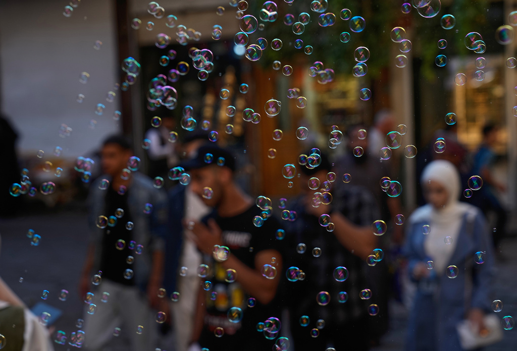 Soap bubbles float in the air as people walk through the old city of Damascus, Syria, Thursday, Oct. 2, 2025. (AP Photo/Hussein Malla)