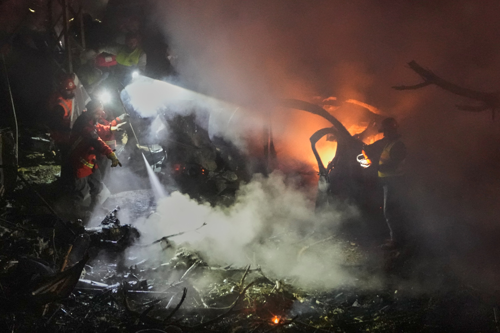 Rescue workers inspect the scene of an Israeli airstrike as fires burn among damaged vehicles, in Beirut, Lebanon, Wednesday, April 1, 2026. (AP Photo/Hussein Malla)