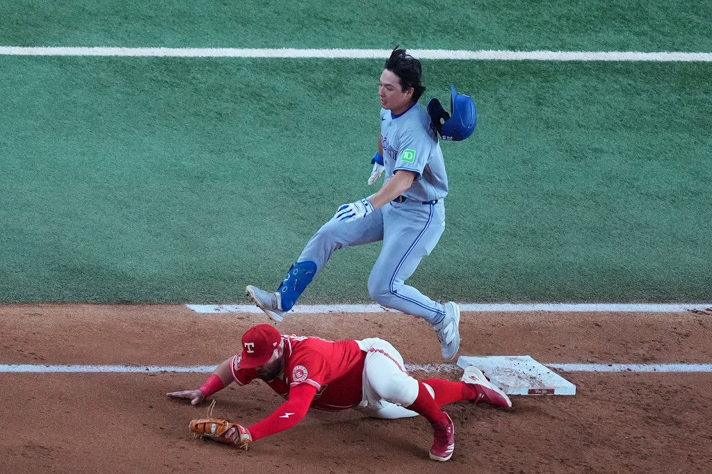 Texas Rangers first baseman Jake Burger, bottom, puts out Toronto Blue Jays' Brett Bateman on a groundout during the third inning of a baseball game Friday, Sept. 18, 2026, in Arlington, Texas. (AP Photo/Julio Cortez)