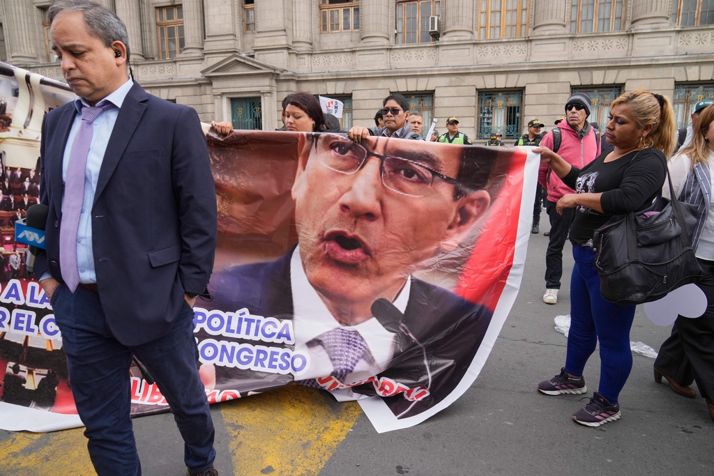 Supporters of former President Martin Vizcarra, who faces corruption charges, carry a banner featuring Vizcarra as they gather outside a courtroom in Lima, Peru, Wednesday, Nov. 26, 2025.(AP Photo/Martin Mejia)