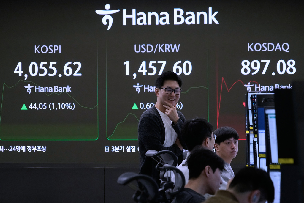 A currency trader exchanges a conversation with his colleagues near a screen showing the Korea Composite Stock Price Index (KOSPI), top left, and the foreign exchange rate between U.S. dollar and South Korean won, top center, at the foreign exchange dealing room of the Hana Bank headquarters in Seoul, South Korea, Monday, Nov. 17, 2025. (AP Photo/Ahn Young-joon)