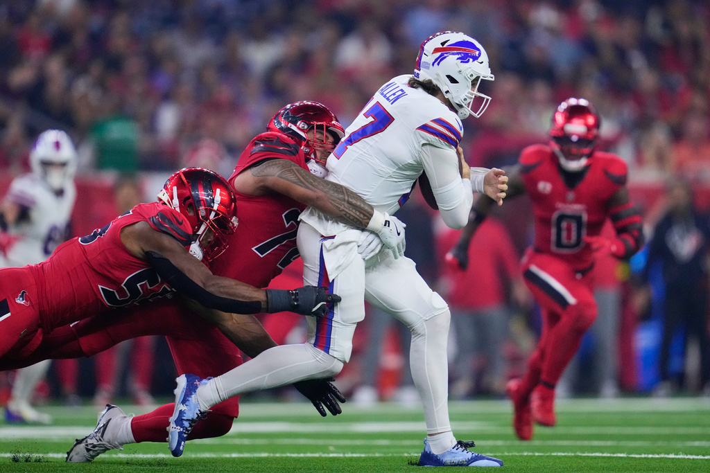 Houston Texans' Danielle Hunter, left, and Tommy Togiai, center, sack Buffalo Bills quarterback Josh Allen (17) in the second half of an NFL football game Thursday, Nov. 20, 2025, in Houston. (AP Photo/Ashley Landis)