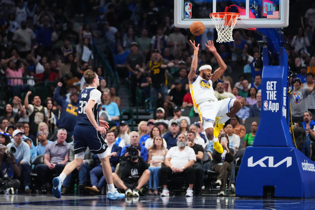 Golden State Warriors guard Moses Moody, right, reacts while suffering an injury as Dallas Mavericks forward Cooper Flagg (32) looks on during overtime of an NBA basketball game Monday, March 23, 2026, in Dallas. (AP Photo/Julio Cortez)