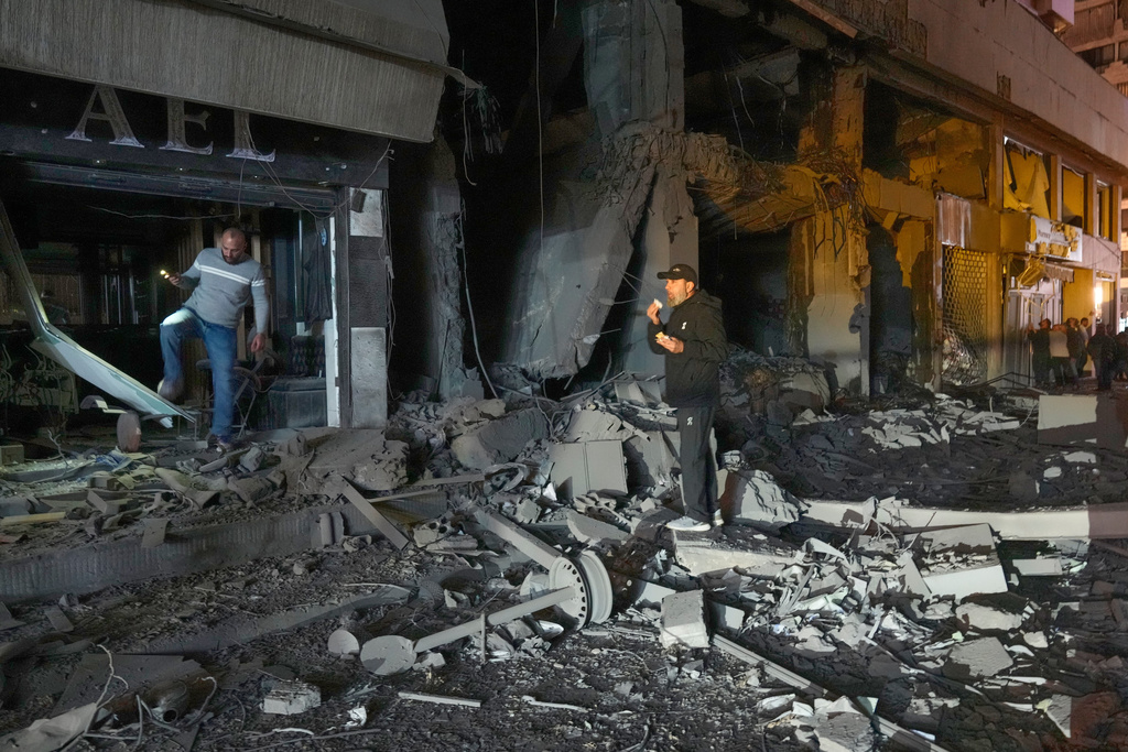 People check the site of a destroyed branch of Al-Qard Al-Hassan, a non-bank financial institution run by Hezbollah, which was hit by an Israeli airstrike in central Beirut, Thursday, March 12, 2026. (AP Photo/Hussein Malla)