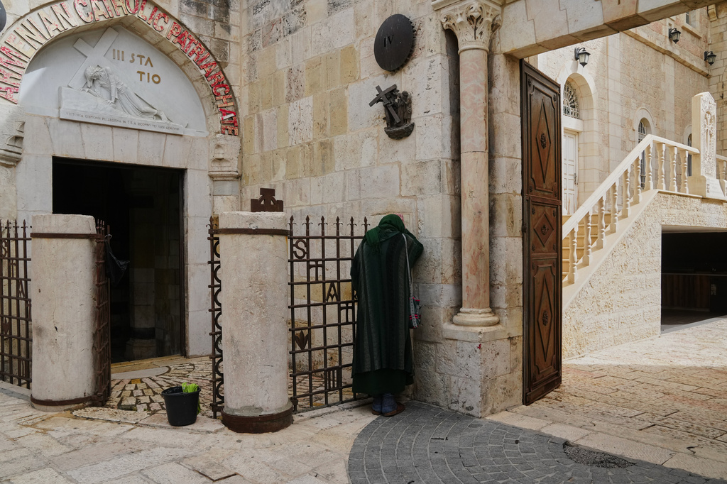 A Christian pilgrim prays at the third station along the Via Dolorosa in Jerusalem's Old City, largely empty due to restrictions linked to the Iran war, during Good Friday, April 3, 2026. (AP Photo/Mahmoud Illean)