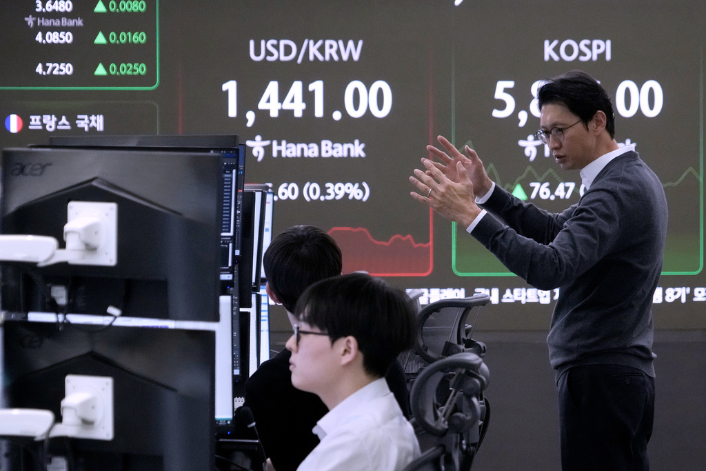 A currency trader reacts near a screen showing the Korea Composite Stock Price Index (KOSPI), right, and the foreign exchange rate between U.S. dollar and South Korean won at the foreign exchange dealing room of the Hana Bank headquarters in Seoul, South Korea, Monday, Feb. 23, 2026. (AP Photo/Ahn Young-joon)