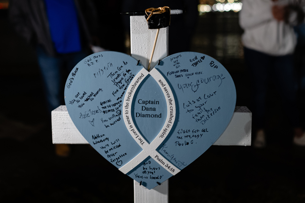 A placard and cross honoring Capt. Dana Diamond is seen during a vigil for those killed and missing after a UPS plane crashed, at the Great Lawn, Friday, Nov. 7, 2025, in Louisville, Ky. (AP Photo/Jon Cherry)