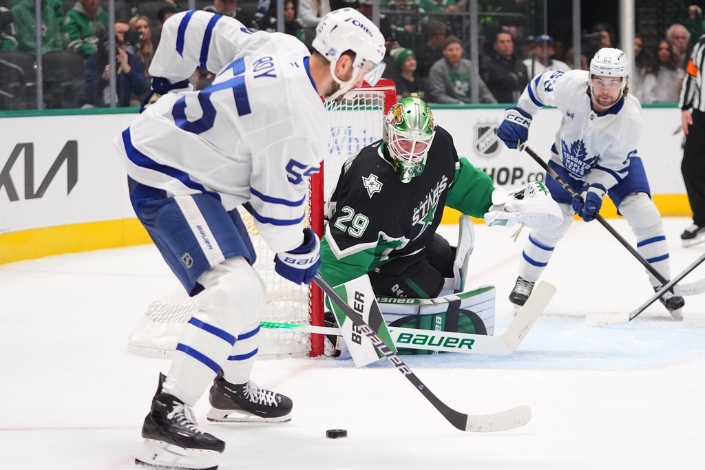 Dallas Stars goaltender Jake Oettinger (29) defends the goal against Toronto Maple Leafs center Nicolas Roy (55) and left wing Matias MacCelli (63) during the second period of an NHL hockey game Sunday, Dec. 21, 2025, in Dallas. (AP Photo/LM Otero)