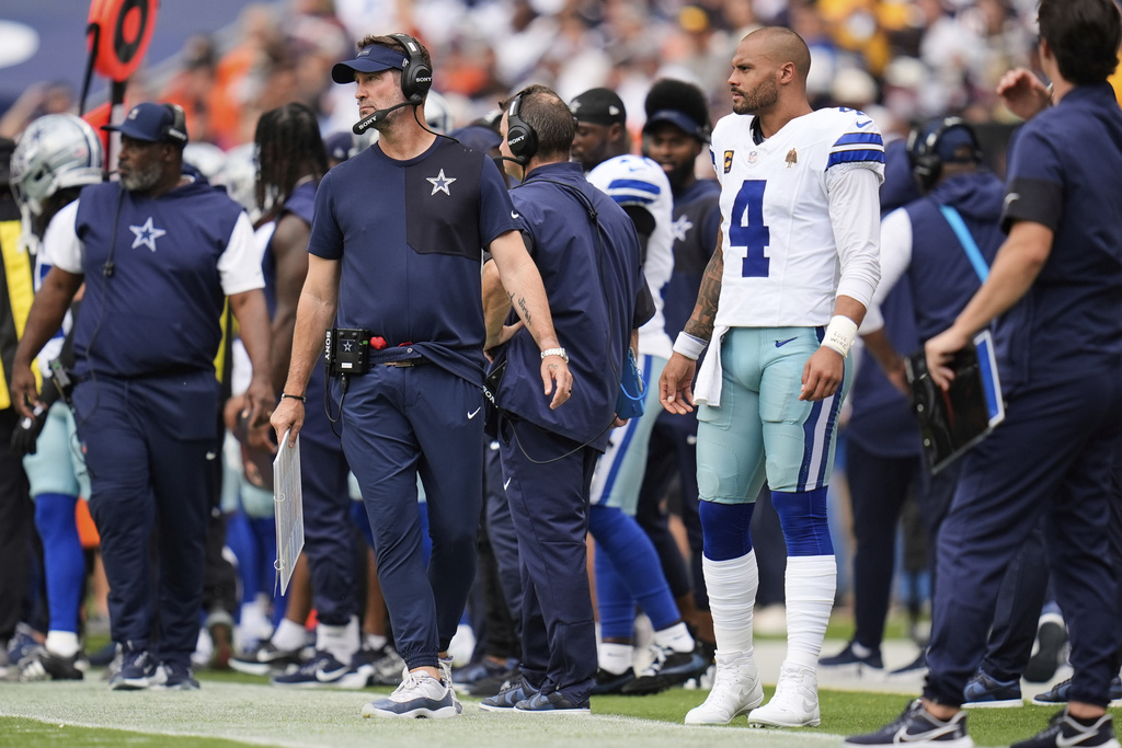 Dallas Cowboys head coach Brian Schottenheimer, center left, adn quarterback Dak Prescott (4) watch play against the Chicago Bears in the first half of an NFL football game Sunday, Sept. 21, 2025, in Chicago. (AP Photo/Erin Hooley)